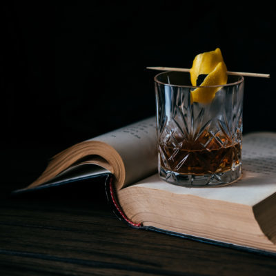 Cocktail Glass of whiskey or cocktail and old book